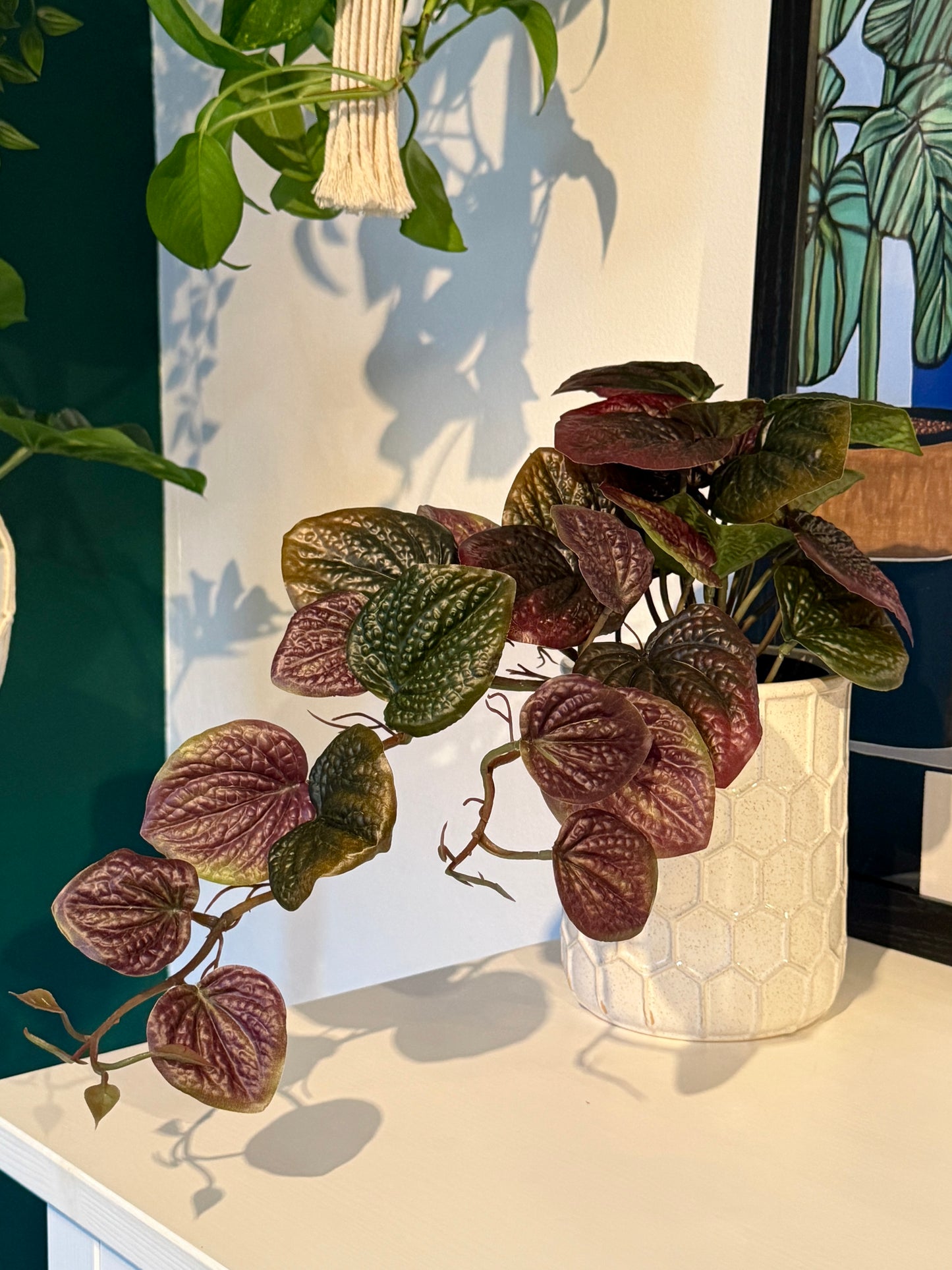 Back view of the Plantish artificial Purple Pothos with its cascading vines and vibrant green and purple leaves, potted in a white honeycomb ceramic pot.
