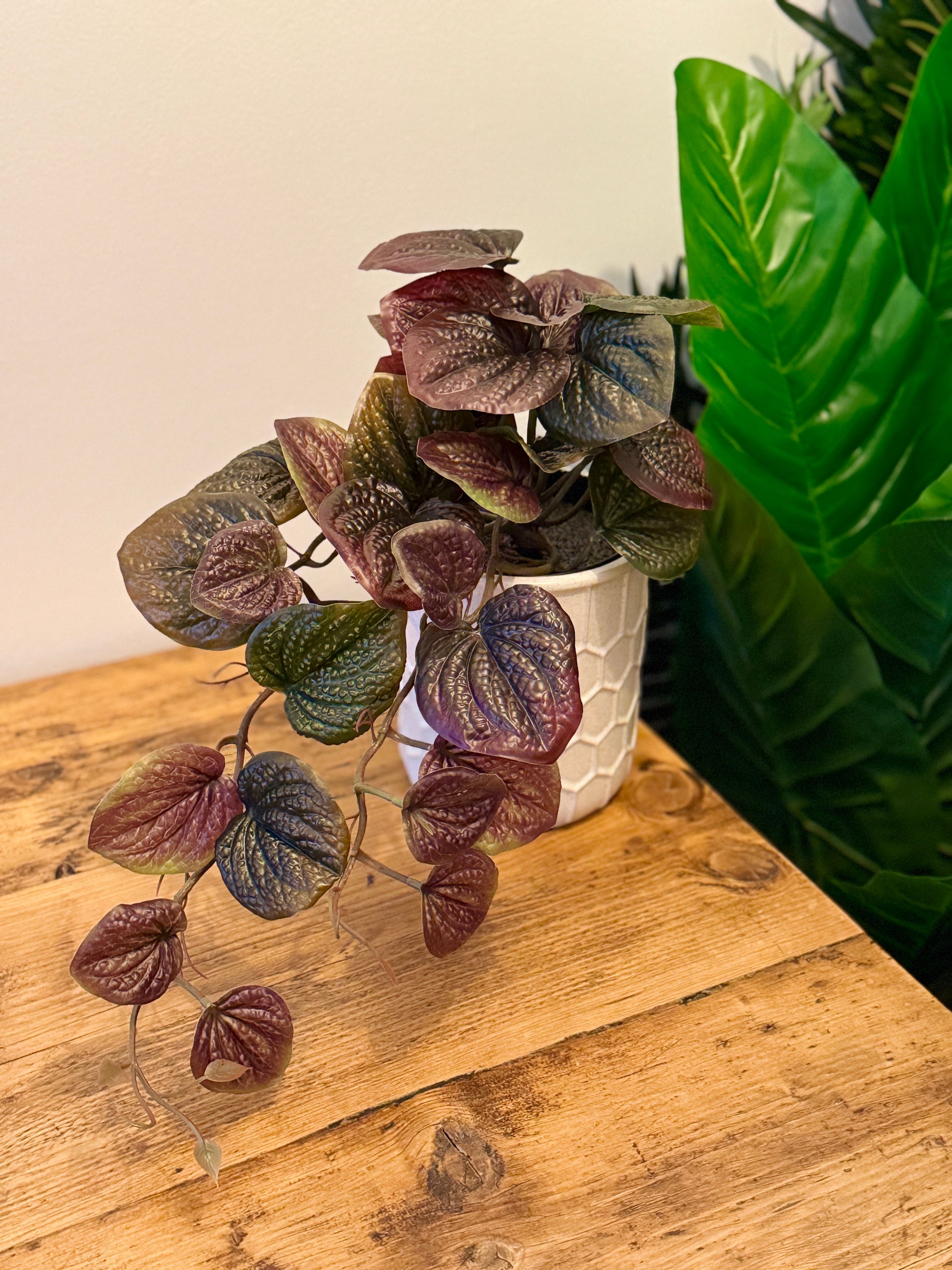 Front view of the Plantish artificial Purple Pothos with lush purple and green leaves and cascading vines, potted in a white honeycomb ceramic pot. 
