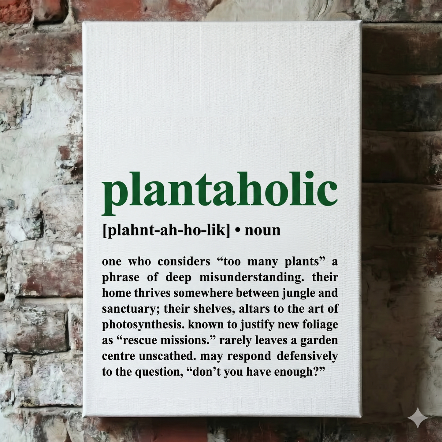 A Plantish canvas of the phrase "Plantaholic" in the style of a dictionary definition, showing the pronunciation against a white background, hanging on a red brick wall.