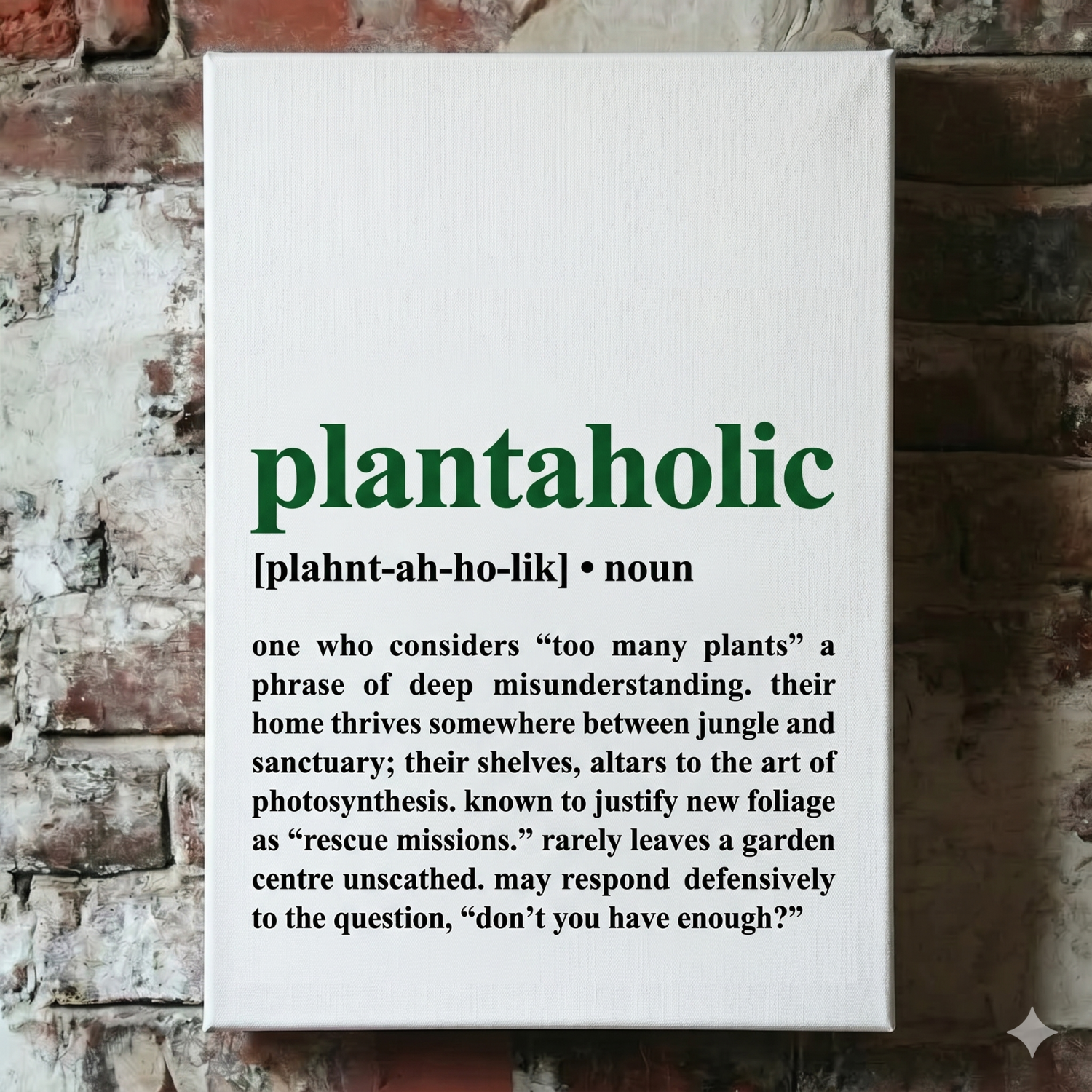 A Plantish canvas of the phrase "Plantaholic" in the style of a dictionary definition, showing the pronunciation against a white background, hanging on a red brick wall.