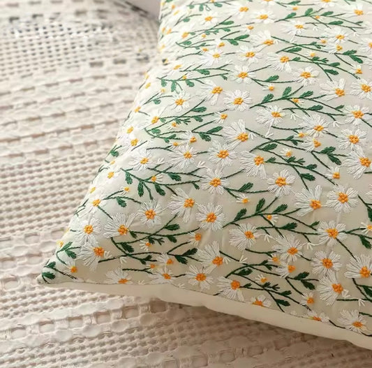 A close up of the Plantish Embroidered Little Daisy Cushion, highlighting the delicate white and yellow flowers and green stems design. 