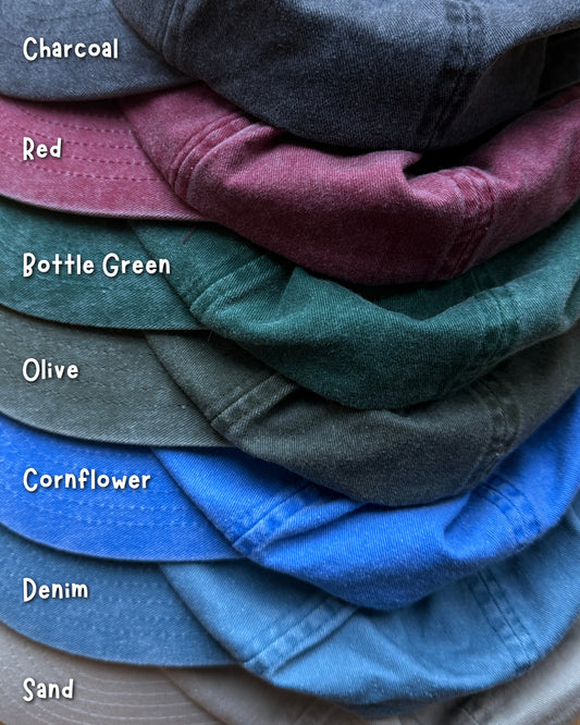 Stack of Plantish hat samples in charcoal, red, bottle green, olive, cornflower, denim and sand.