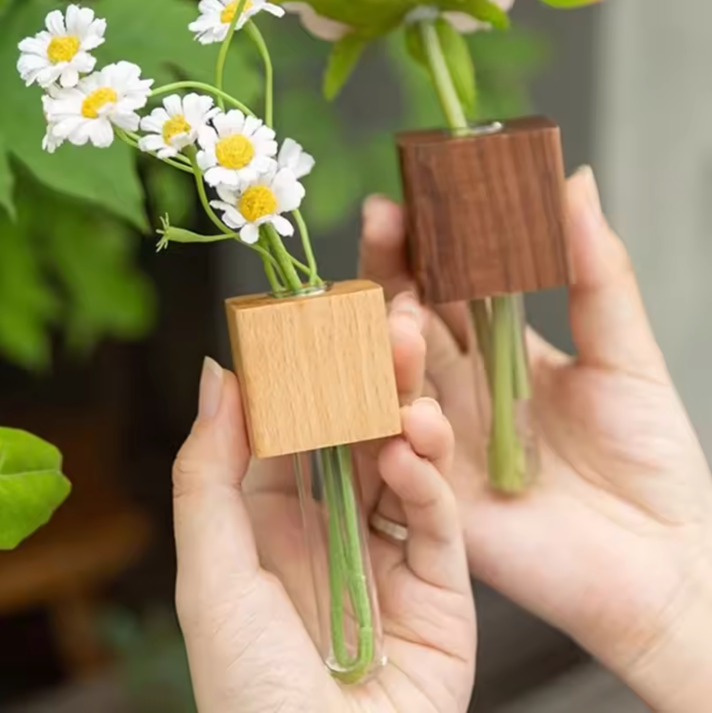 The Plantish Propagation Fridge Magnet in both variants, being held in a bright plant corner. There are white flowers inside both