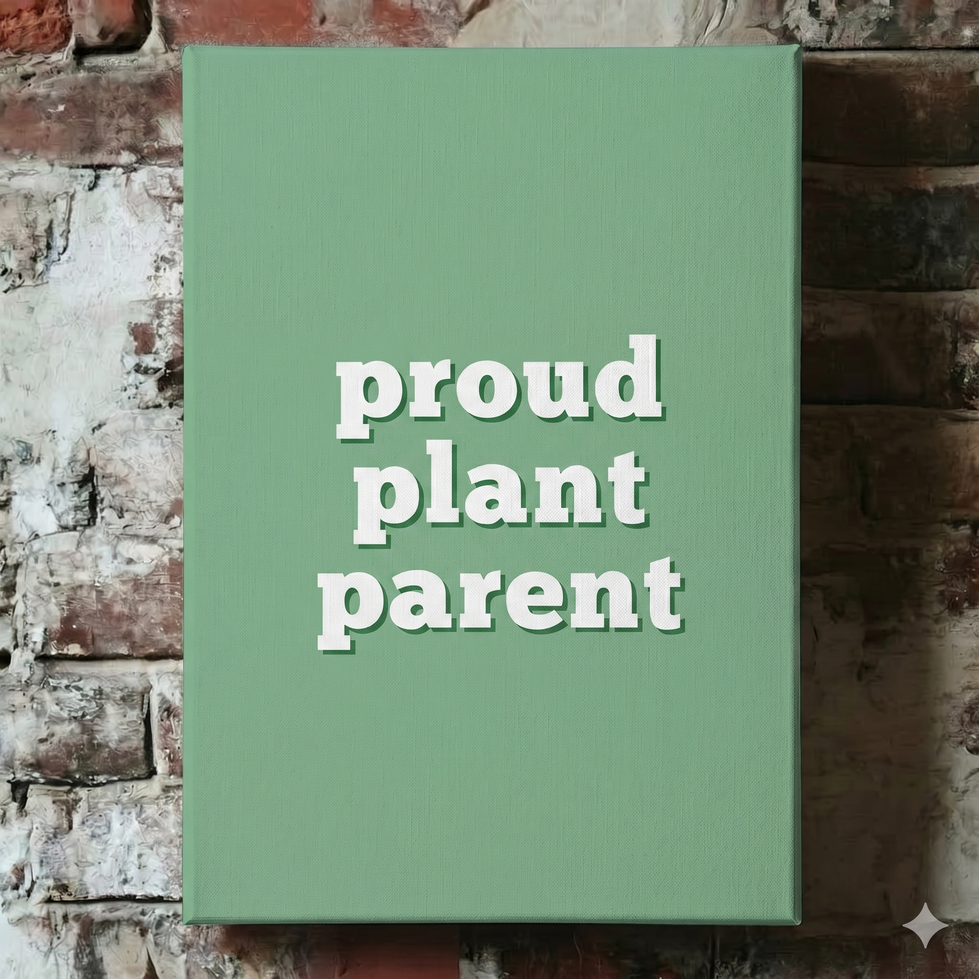 A Plantish canvas of the phrase "Proud Plant Parent" in a white font with a green background, shown hanging on a red brick wall.