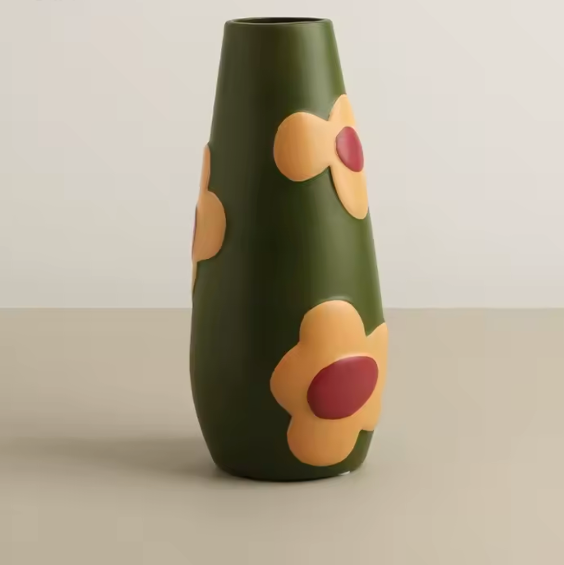 The Plantish Retro Floral Ceramic Vase in Green, shown shown against a plain cream table and white wall. 
