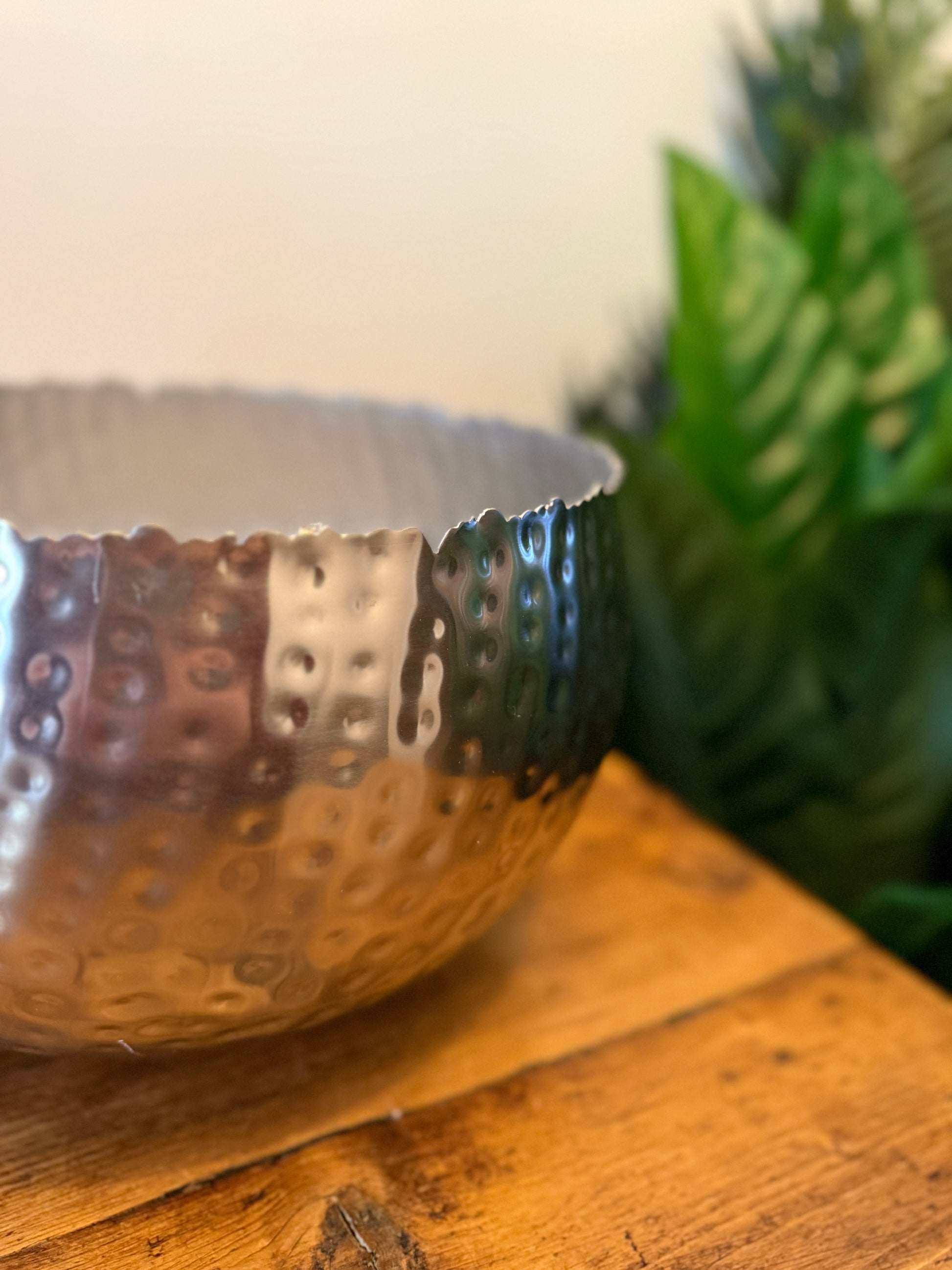 Close up of a large hammered silver-coloured metal planter, highlighting its textured surface.