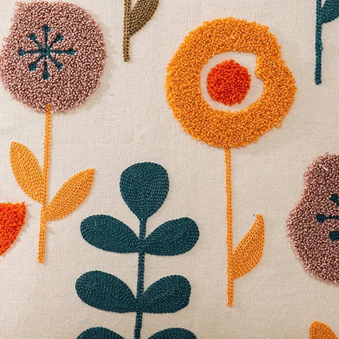 A close up of the Plantish Tufted Scandinavian Cushion Cover Funky Flower design, showing the detailed embroidered details in green, orange, and lilac.