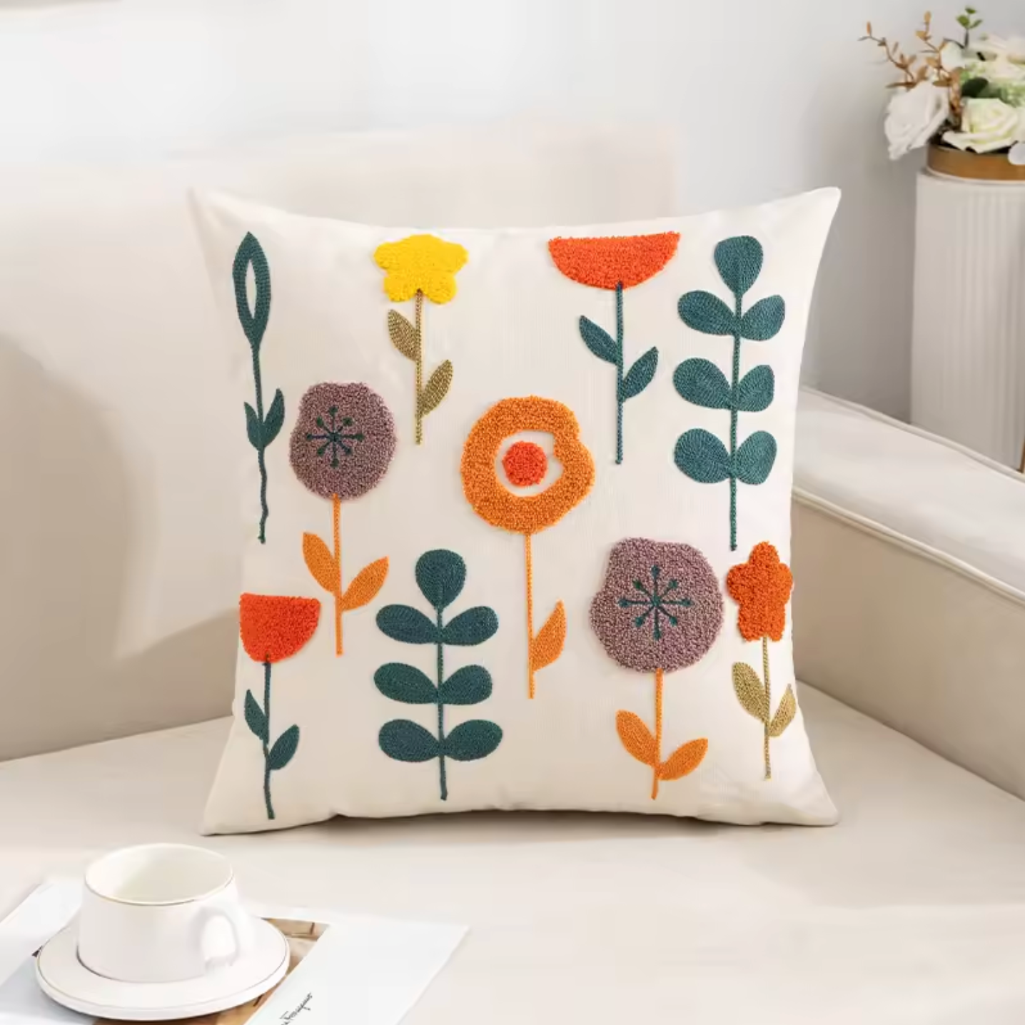 A close up of the Plantish Tufted Scandinavian Cushion Cover in Funky Flowers design, positioned on a white sofa next to a cup and saucer.
