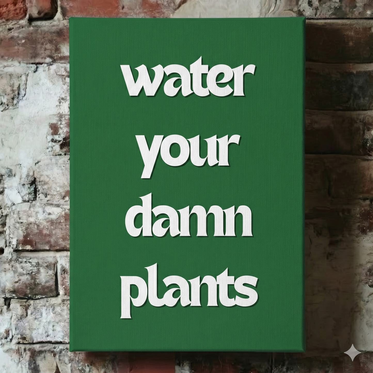 A Plantish canvas showing the phrase "Water Your Damn Plants" in a white font against a green background, hanging on a red brick wall.