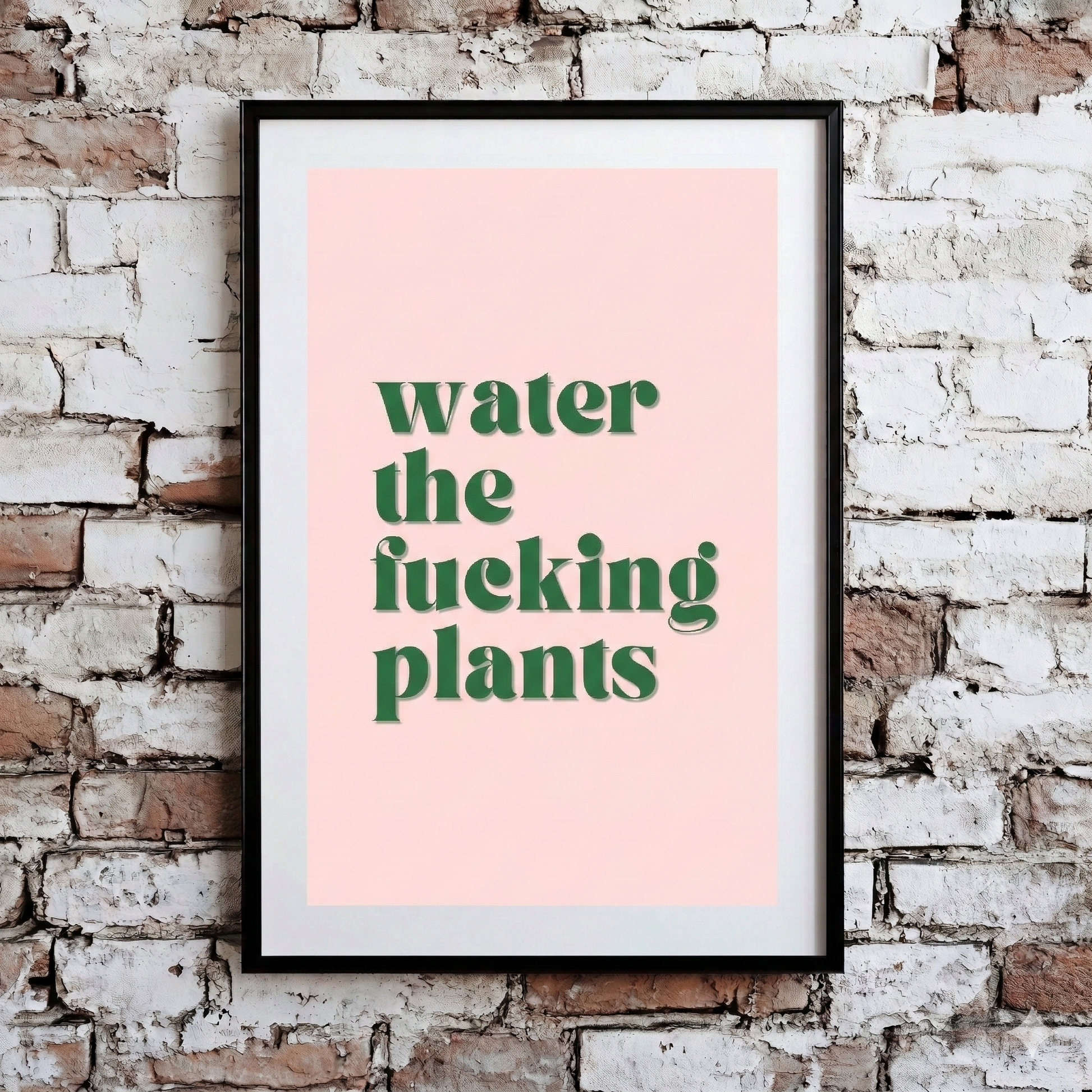 A Plantish print showing the phrase "Water the Fucking Plants" in a green font against a pink background, hanging on a brick wall.