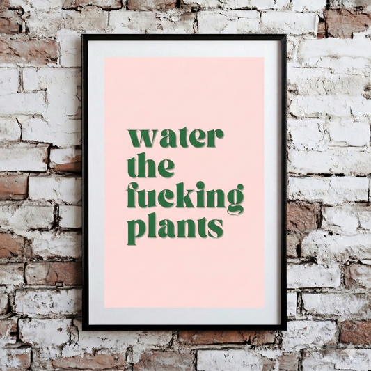 A Plantish print showing the phrase "Water the Fucking Plants" in a green font against a pink background, hanging on a brick wall.