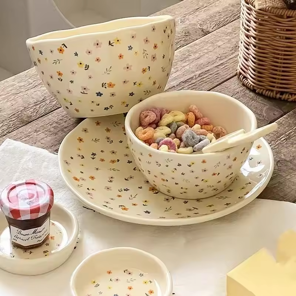 A full set of the Plantish Wildflower collection, with small & large bowls, a plate, and two sauce dishes. Everything is on a wooden table.