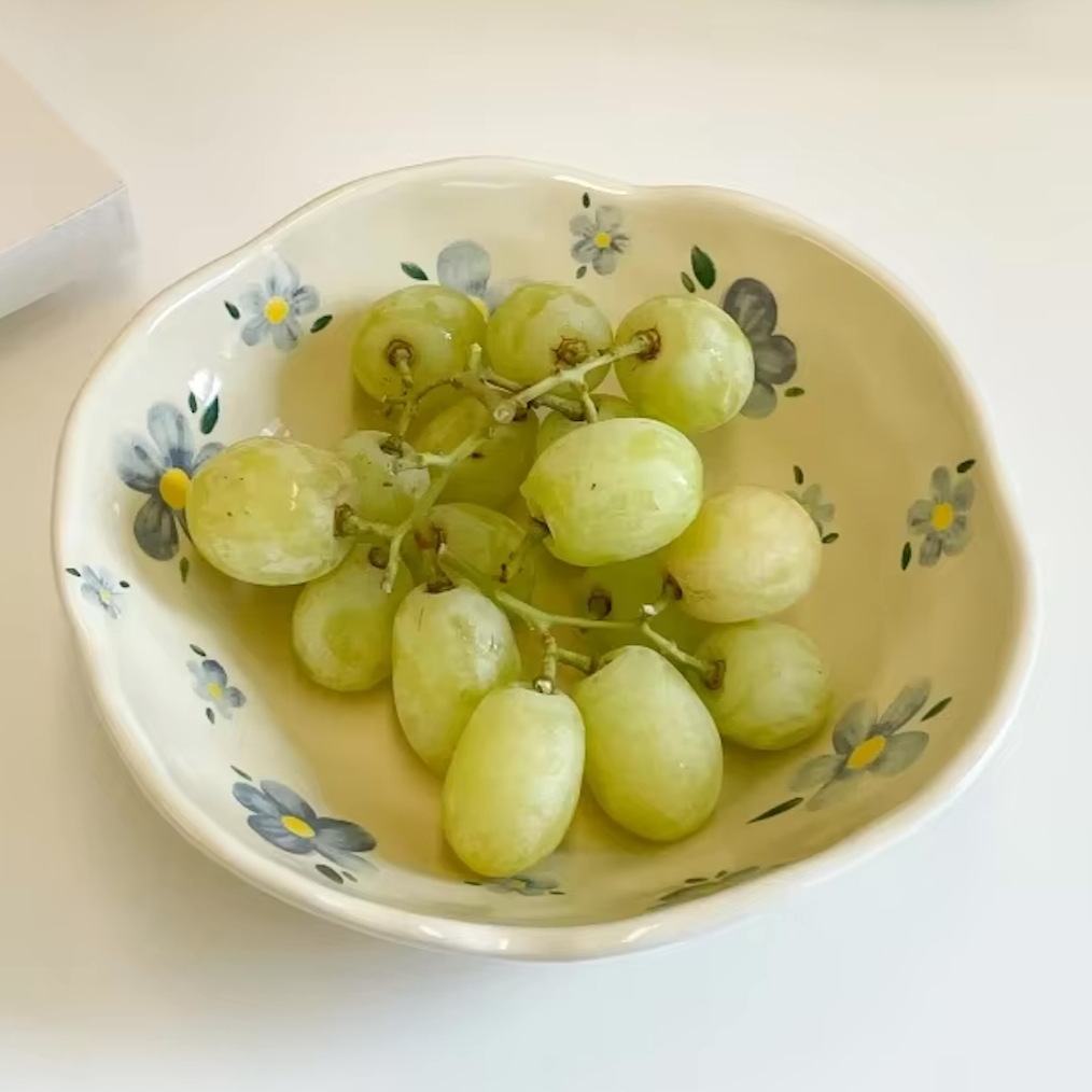 Close up of the Plantish Wonky Flower Plate Blue Flower design, the plate has a bunch of green grapes inside and is positioned on a table. 