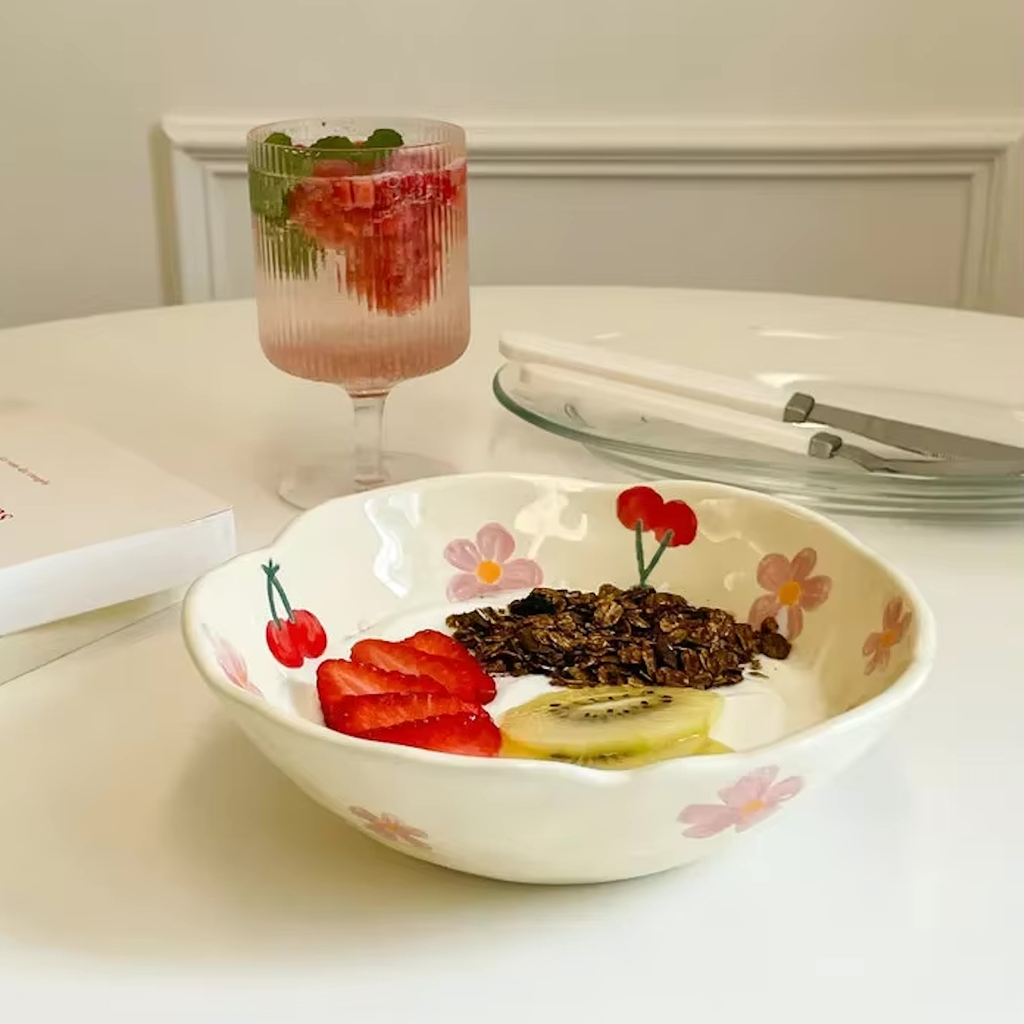 Close up of the Plantish Wonky Flower Plate Cherry Blossom design, the plate has yoghurt topped with fruit inside and is positioned on a white table. 