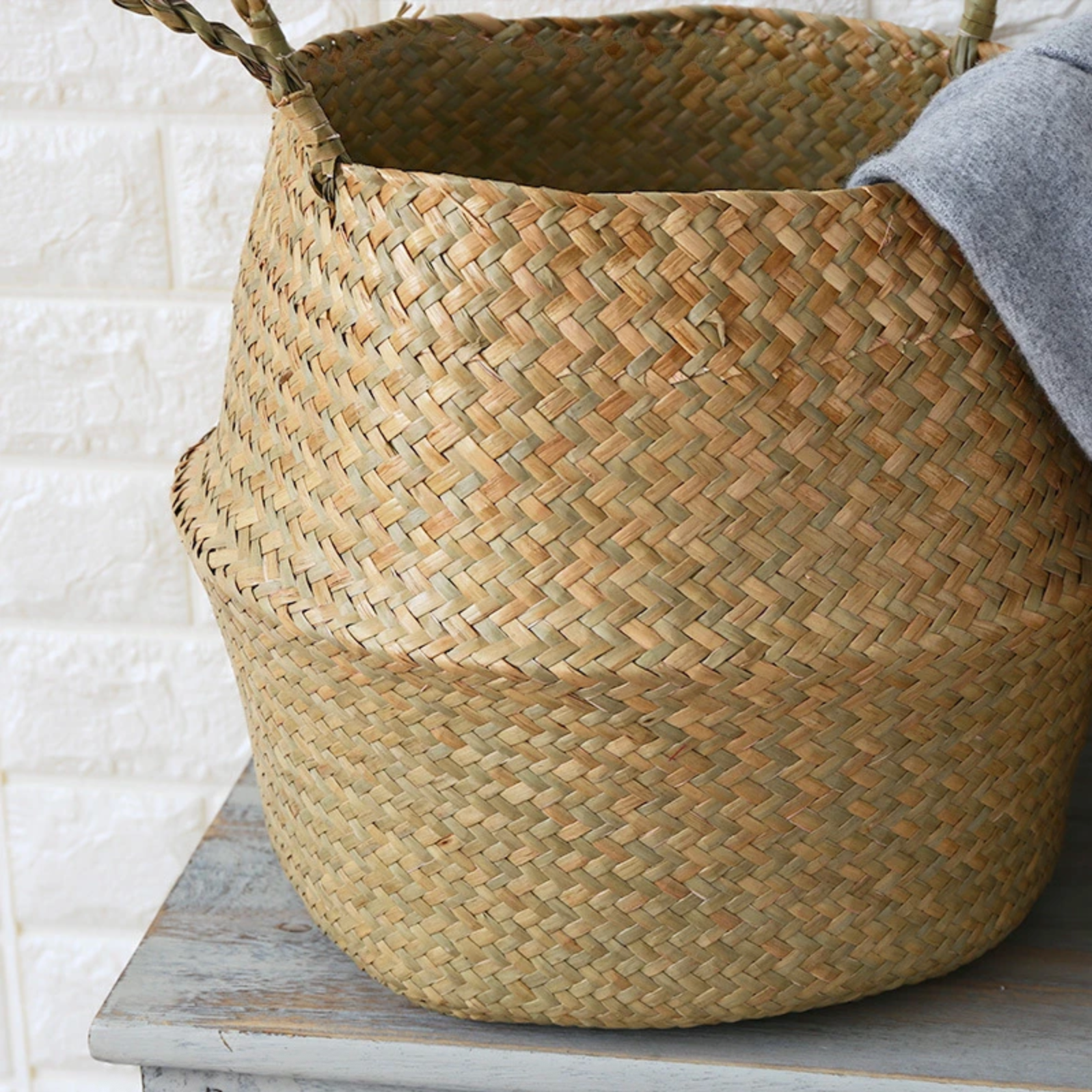 A close up of the Plantish Woven Wicker Basket fully extended, highlighting the detailed weave of the seagrass material. It is on a wooden table.